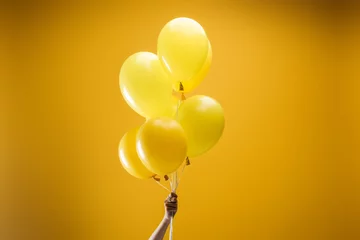 Foto op Canvas cropped view of woman holding festive bright minimalistic decorative balloons on yellow background © LIGHTFIELD STUDIOS