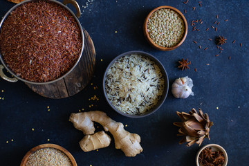 Various types of rice and grains with spices on blue background. Brown rice and mixed wild rice.