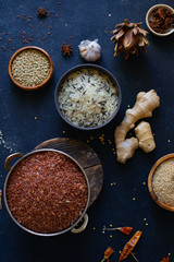 Various types of rice and grains with spices on blue background. Brown rice and mixed wild rice.