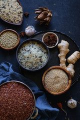 Various types of rice and grains with spices on blue background. Brown rice and mixed wild rice.