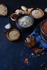 Various types of rice and grains with spices on blue background. Brown rice and mixed wild rice.