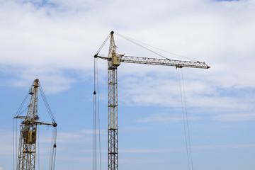 Fototapeta premium Industrial construction building cranes against blue cloudy sky