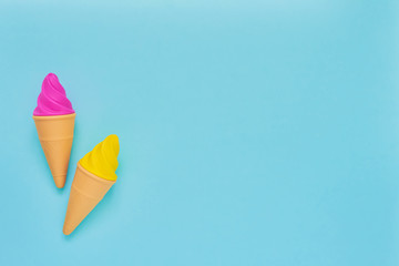 Pink and yellow toy ice-cream on light blue background. Minimalism, summer concept. - obrazy, fototapety, plakaty