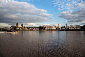 Naklejka premium Thames River commuter ferry passing Greenwich riverfront buildings