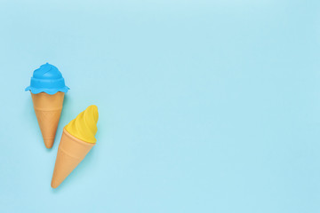 Blue and yellow toy ice-cream on light blue background. Summer concept. Top view, copy space.