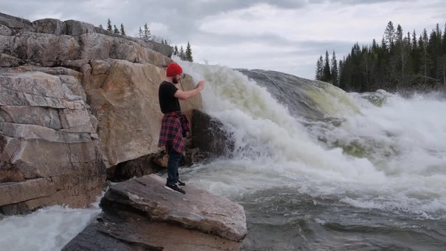 tourist stands under a waterfall, takes pictures how does water flow