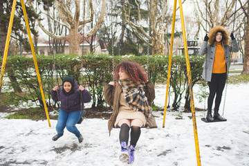 group of young multiracial women having fun on the swing in play area