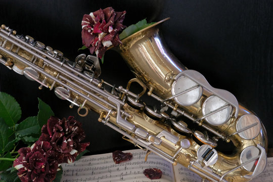 Old saxophone and black roses. Romantic music background.