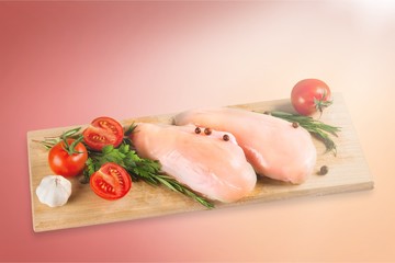 Raw turkey breasts with vegetables, spice and herbs on wooden cutting boardRaw turkey breast with tomatoes and garlic on cutting board