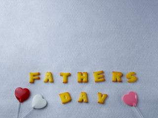 Biscuits, letters, shapes And heart shaped lollipop, arranged on a white background for Father's Day