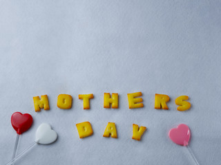 Biscuits, letters, shapes And heart shaped lollipop, arranged on a white background for Mother's Day