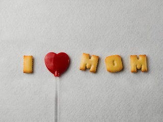 Biscuits with letter shapes And a red heart-shaped lollipop, arranged in a message “I Love Mom” For Mother's Day