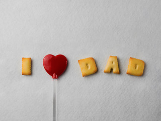 Biscuits with letter shapes And a red heart-shaped lollipop, arranged in a message “I Love Dad” For Father's Day