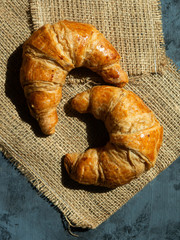 Fresh butter croissants on a mat that is placed on a dark gray wood table