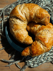 Fresh butter croissants on a gray plate that is placed on a dark gray wood table and decoration.
