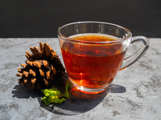Hot tea in a clear glass that is placed on a dark gray table and decoration