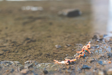 Miniature people wearing swimsuit relaxing on the beach , Summer concept