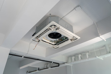 Four-way air conditioner mounted on the ceiling of the room, used for home or office.