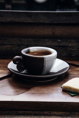 Espresso coffee in a black and white ceramic cup on wooden table at coffee shop. Drink photography concept, minimalism, close up