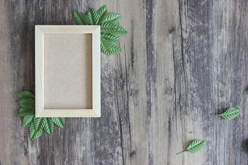 Wood frame and green leaves on wood background. Spring concept