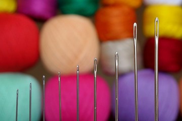 A set of needles for hand sewing on the background of colored threads. Sewing needle closeup