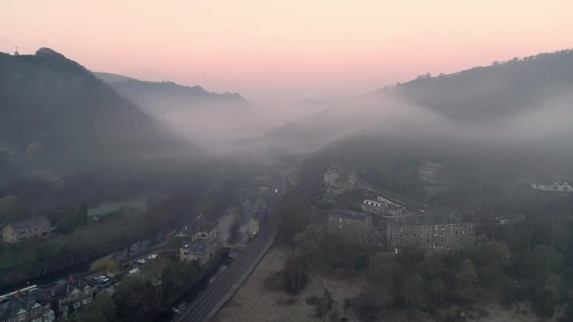 Aerial drone through village in mist at sunrise