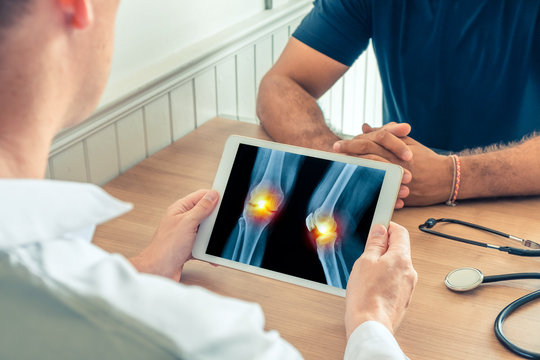 Doctor holding a digital tablet with x-ray of knees of the patient with pain on the knees