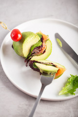 Cutted organic raw avocado burger with salted salmon and fresh vegetables.