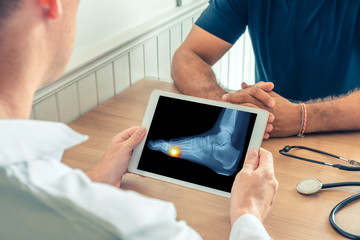 Doctor holding a digital tablet with x-ray of foot of the patient. Pain under the foot