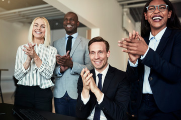 Group of businesspeople smiling and clapping after an office pre