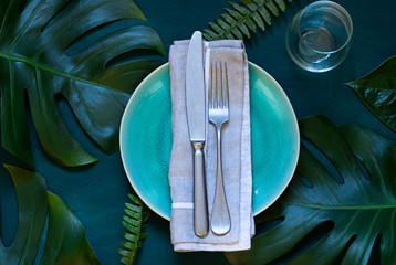 Summer table settings concept empty plate frame on the wooden dark background with tropical leaves....