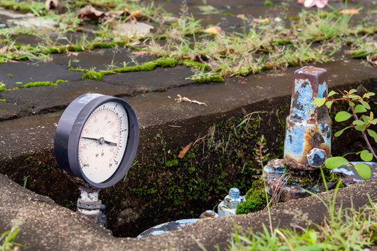 Old monometer installed on the pipeline in a concrete well on a city street
