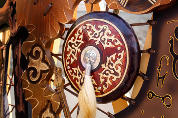 Traditional shield of an ancient Asian warrior with a horsehair brush against the background of national symbols. Close-up