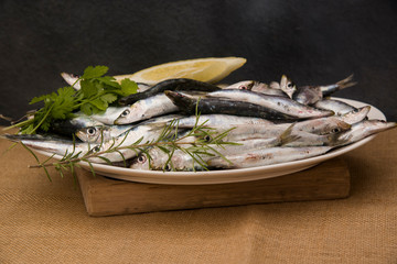 fresh sardines on a tray with lemon slices