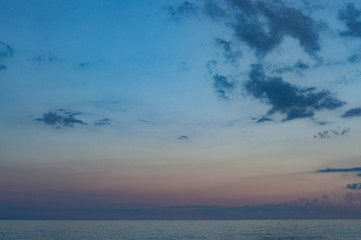 Gradient sky colors from violet through pink to blue shades. Picturesque cloudscape above calm sea in dusk with fluffy clouds in clear light sky. Summer sunset seascape of Black sea 