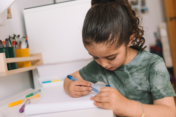 little girl drawing at home with color markers