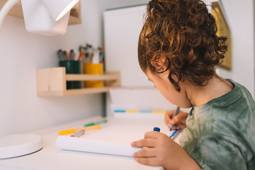 little girl drawing in her room with markers