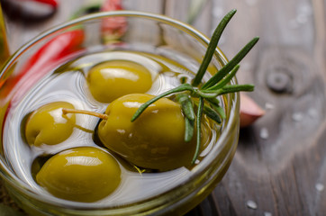 Closeup view of green olives oils and spices on kitchen table. Cooking concept