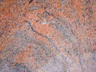 Background red natural granite stone. Black and light blotches and patterns. Texture. Polished surface with a crystalline structure.