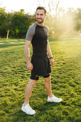 Handsome young strong sports man posing outdoors at the nature park location make exercises with...