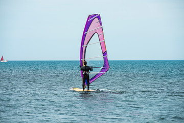 A windsurfer rides on the sea in calm, light wind.