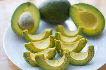 slice of avocado on white dish for healthy fruit. soft focus.