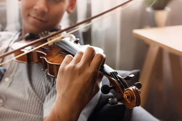 In selective focus of human hand pressing on string,show how to play violin,blurry light around © Watcharin