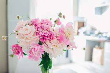 Pink peonies. Modern kitchen design. Interior of white and silver kitchen decorated with flowers.