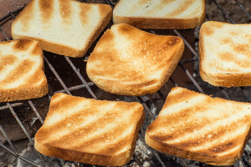 Cooking grilled toast on the coal grill. Fried toast is a common food at outdoor parties of friends.