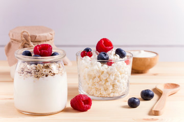 cottage cheese and yogurt with fresh berries in glass jars on a wooden table. rustic style.