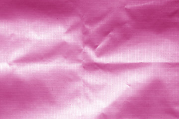 Fototapeta na wymiar Crumpled transparent plastic surface in pink color.