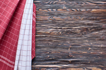 Old dark wooden background. Wooden table with red and white kitchen towels
