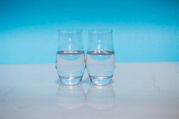 Half-full water glasses, two half-empty water glasses against a blue background