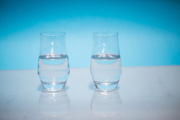 Half-full water glasses, two half-empty water glasses against a blue background